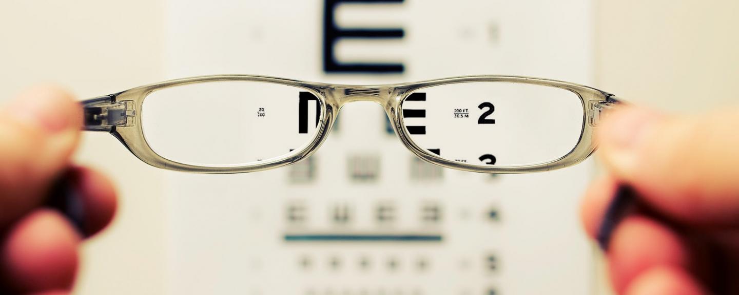 Glasses being held up infront of an eye test