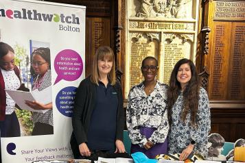 3 ladies standing by a Healthwatch Bolton banner