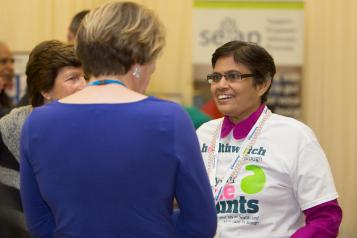 Woman wearing Healthwatch clothing talking to another woman 