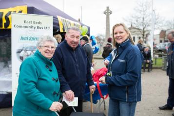 Woman wearing a Healthwatch jacket stood with two members of the public