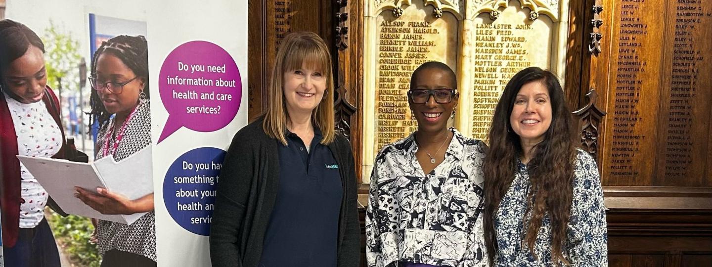 3 ladies standing by a Healthwatch Bolton banner