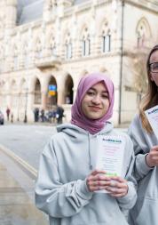 Two young teenagers holding up Healthwatch promotional material