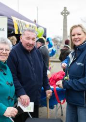 Woman wearing a Healthwatch jacket stood with two members of the public